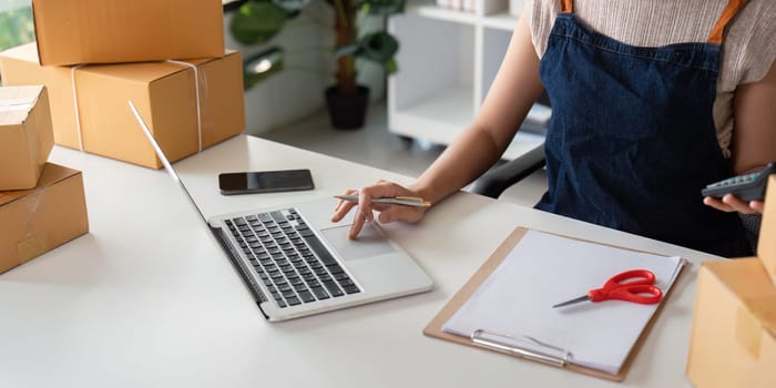 Woman in an online store check the customer address and package information on the laptop. Online shopping concept.