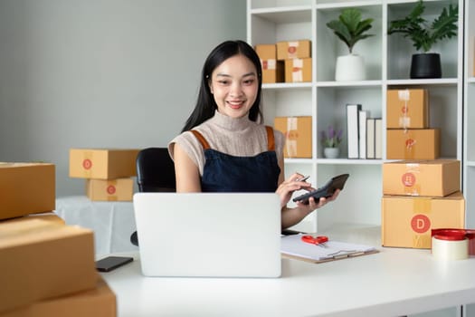 Young business woman asian working online ecommerce shopping at her shop. Young woman sell prepare parcel box of product for deliver to customer. Online selling.