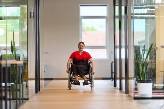 A modern young businesswoman in a wheelchair is surrounded by an inclusive workspace with glass-walled offices, embodying determination and innovation in the business world.