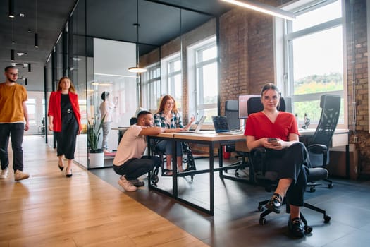 A diverse group of business professionals collaborates in a modern startup coworking center, utilizing a mix of paper-based and technological tools such as mobile phones and computers .