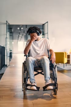 A African-American teenager in a wheelchair sits sadly amidst the bustling backdrop of a modern startup office, surrounded by his business colleagues