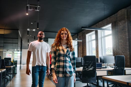 An African-American business colleague and his orange-haired female counterpart engage in collaborative discussion within a modern startup office, epitomizing diversity and teamwork in the entrepreneurial environment.