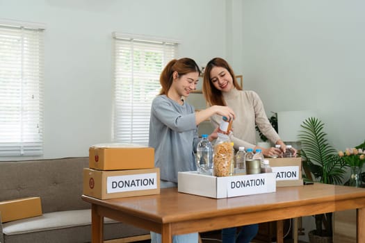 charity, donation and volunteering concept. Volunteer prepare foodstuff box containing food to donate to people poor, disaster victim at home.