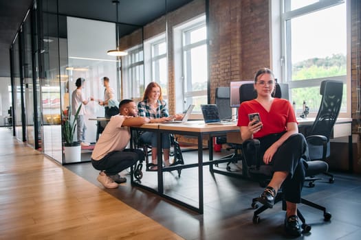 A diverse group of business professionals collaborates in a modern startup coworking center, utilizing a mix of paper-based and technological tools such as mobile phones and computers .