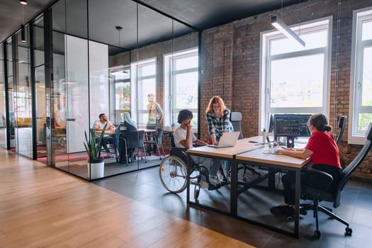 A diverse group of business professionals collaborates in a modern startup coworking center, utilizing a mix of paper-based and technological tools such as mobile phones and computers .