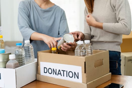 charity, donation and volunteering concept. Volunteer prepare foodstuff box containing food to donate to people poor, disaster victim at home.