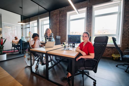 A diverse group of business professionals collaborates in a modern startup coworking center, utilizing a mix of paper-based and technological tools such as mobile phones and computers .