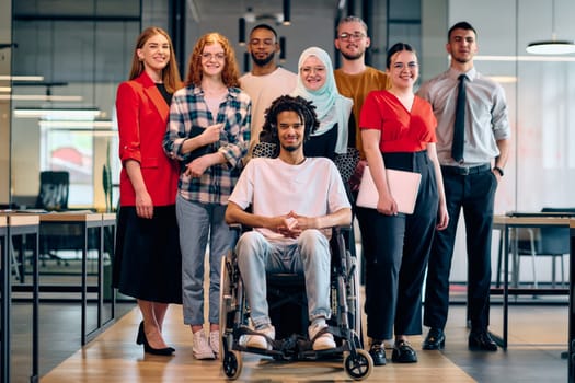 A diverse group of young business people walking a corridor in the glass-enclosed office of a modern startup, including a person in a wheelchair and a woman wearing a hijab.