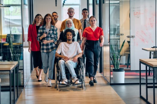 A diverse group of young business people congregates within a modern startup's glass-enclosed office, featuring inclusivity with a person in a wheelchair, an African American young man, and a hijab muslim woman