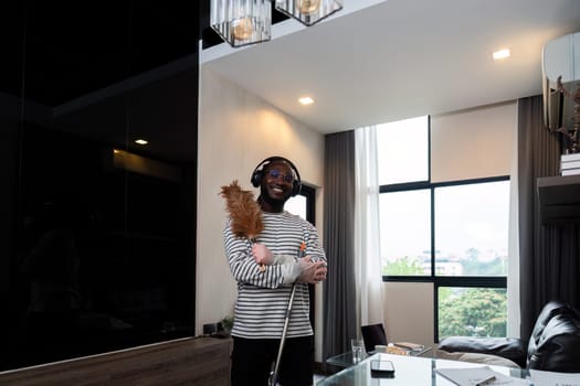 Young African American man for cleaning apartment, holding mop and other cleaning tools. Cheerful african american man housekeeping on weekend.