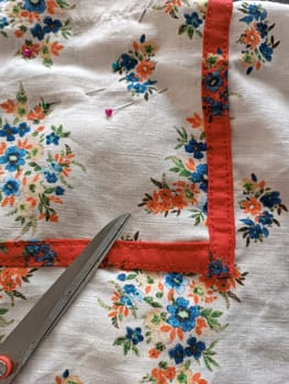 Colourful red and white with flowers linen fabric cloth with sewing scissors on it and needles. High quality photo