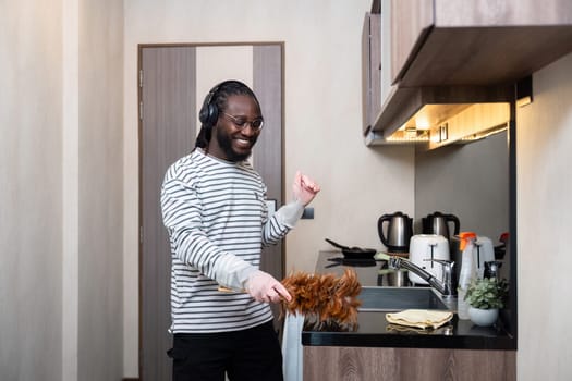 African American man listening to music while cleaning in kitchen.