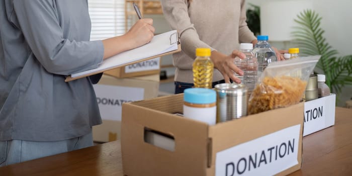 Volunteer preparing free foodstuff rations for poor people. Charity two woman of the community work together. concept of giving and humanitarian aid.