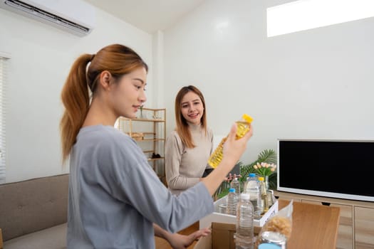 Donation and two woman volunteer asian of happy packing food in box at home. Charity.