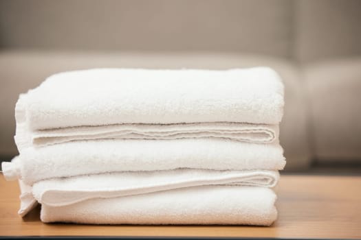 Clean, laundry and soft towel on table for hospitality, cleaning service and white material of fabric. Fresh, textile and pile of linen cloth at home with texture for bathroom, health and hygiene.