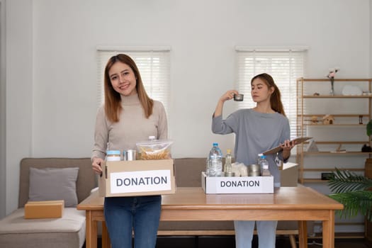 Woman with charity box and group of volunteers at assistance center. Charity, donation, and volunteering concept.