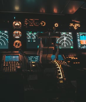 Cockpit view of an airplane during a night-time flight with illuminated instrument panels