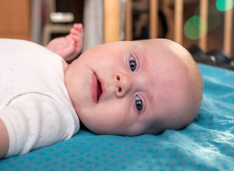 Side view close portrait of adorable newborn baby boy lying on her back on a large bed. Concept of childhood, new life, parenthood.