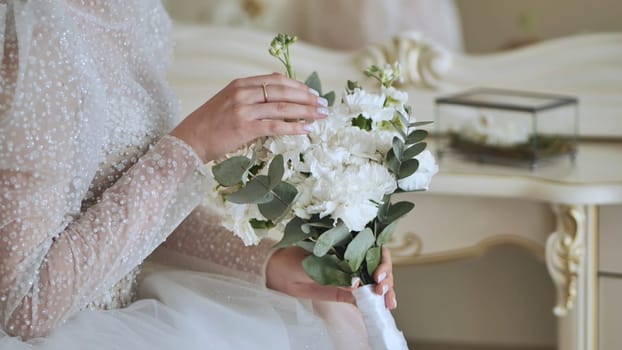 The bride touches the bouquet of flowers