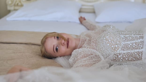 The delicate bride lies and poses on the bed