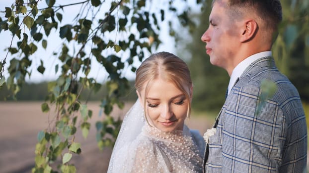 Bride and groom touching and enjoying each other against a backdrop of birch tree branches