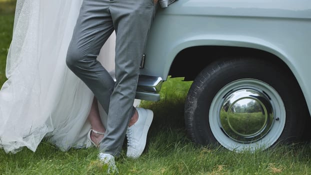 The bride and groom linger by the retro car on their wedding day