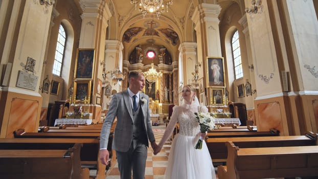 The bride and groom walk and kiss through a Catholic church