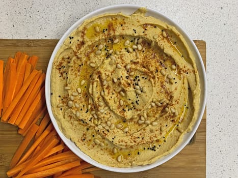 Eating homemade hummus with a piece of fresh carrot.