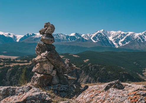 Stone cairn and snowy mountains peaks in the background. Beautiful landscape of Altay region, Russia.