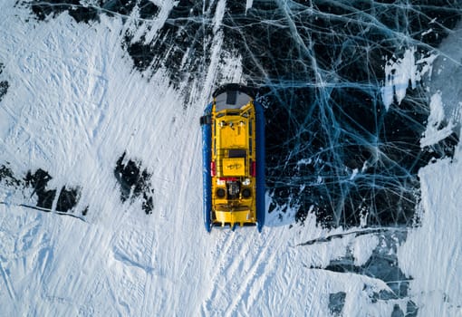 Aerial top down view on a hovercraft parked on the beautiful cracked ice of the lake Baikal. Winter Baikal, frozen lake. Amazing winter landscape.