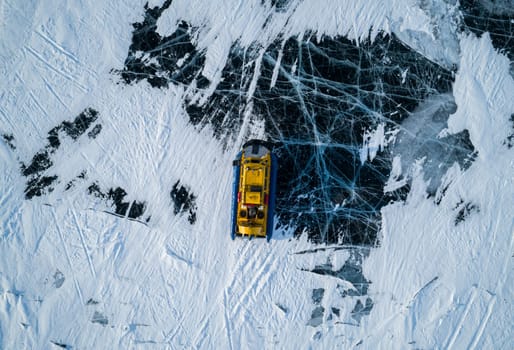 Aerial top down view on a hovercraft parked on the beautiful cracked ice of the lake Baikal. Winter Baikal, frozen lake. Amazing winter landscape.