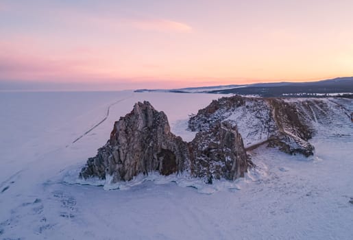 Aerial shot of a Shamanka rock on Olkhon island at sunset. Winter landscape. Popular touristic destination. Natural landmark. Panoramic view.