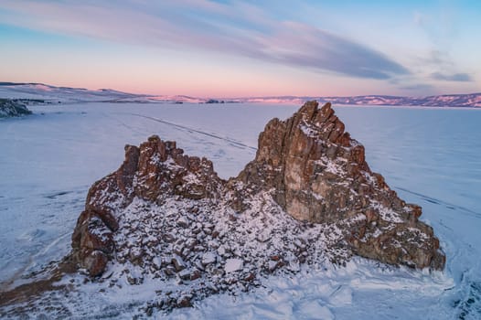 Aerial shot of a Shamanka rock on Olkhon island at sunset. Winter landscape. Popular touristic destination. Natural landmark. Panoramic view.