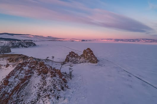 Aerial shot of a Shamanka rock on Olkhon island at sunset. Winter landscape. Popular touristic destination. Natural landmark. Panoramic view.