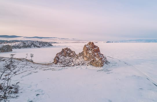 Aerial shot of a Shamanka rock on Olkhon island at sunset. Winter landscape. Popular touristic destination. Natural landmark. Panoramic view.