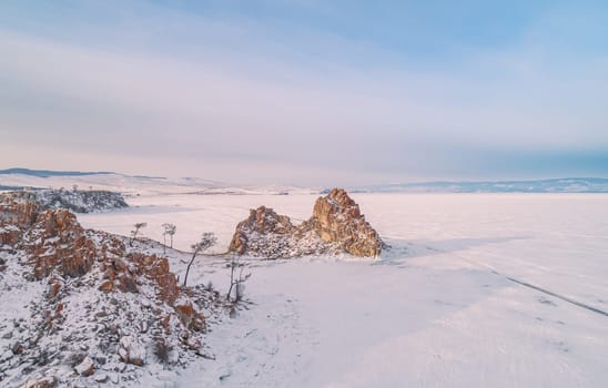 Aerial shot of a Shamanka rock on Olkhon island at sunset. Winter landscape. Popular touristic destination. Natural landmark. Panoramic view.