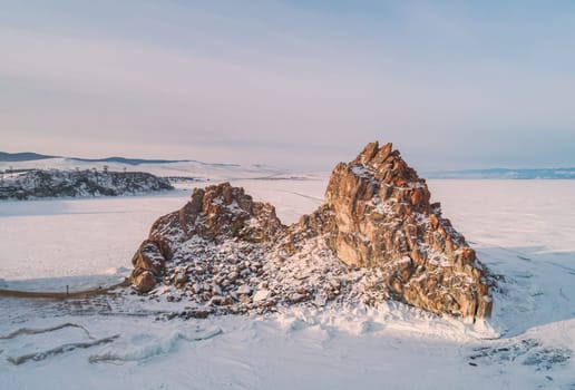 Aerial shot of a Shamanka rock on Olkhon island at sunset. Winter landscape. Popular touristic destination. Natural landmark. Panoramic view.