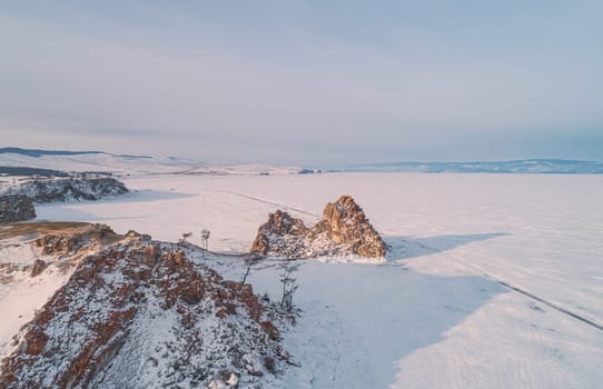 Aerial shot of a Shamanka rock on Olkhon island at sunset. Winter landscape. Popular touristic destination. Natural landmark. Panoramic view.