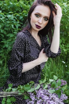 A fashionable girl with dark hair, a spring portrait in lilac tones in summer. Bright professional makeup