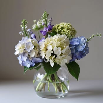 Transparent vase with pink white blue flowers on a light background. Flowering flowers, a symbol of spring, new life. A joyful time of nature waking up to life.