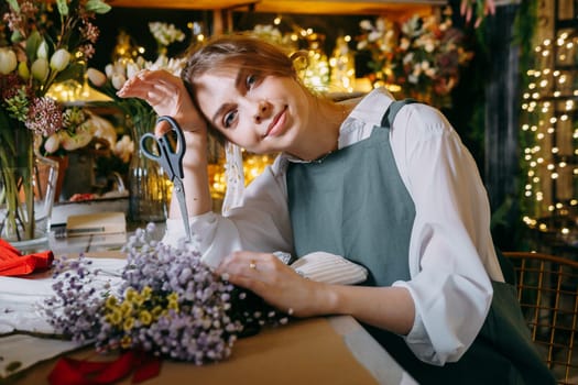 A woman in her florist shop collects bouquets of flowers. The concept of a small business. Bouquets of tulips for the holiday on March 8