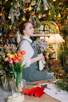 A woman in her florist shop collects bouquets of flowers. The concept of a small business. Bouquets of tulips for the holiday on March 8