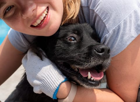 Close-up of girl hugging and petting caged stray dog in pet shelter. People, Animals, Volunteering And Helping Concept.