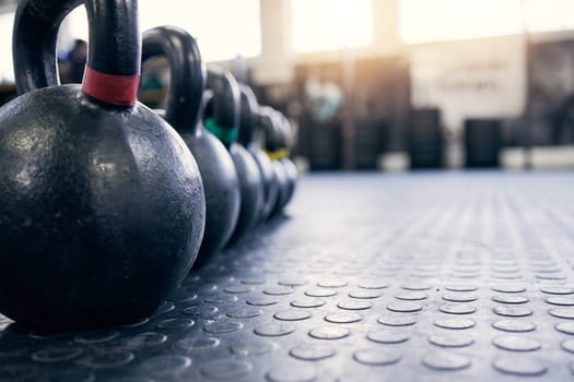 Fitness, kettlebell and weights on floor of gym for training, wellness or workout with space. Background, metal equipment in health club and exercise for action, physical improvement or strength.