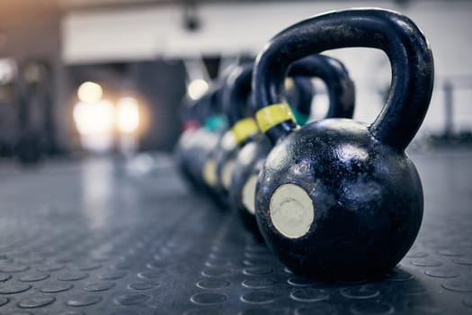 Exercise, kettlebell and weights on floor of gym for training, wellness or workout with space. Background, metal equipment in health club and fitness for action, physical improvement or strength.