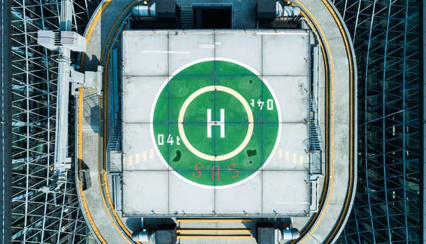 Aerial top view of helipad on the roof of a skyscraper iin downtown with cityscape view on sunny day