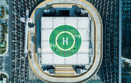 Aerial top view of helipad on the roof of a skyscraper iin downtown with cityscape view on sunny day