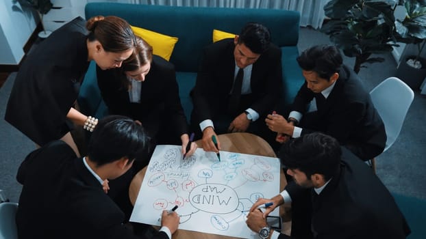 Top view of skilled diverse business people planning project by using mind map to brainstorm marketing idea. Closeup of smart start up team working together to draw creative mind map. Directorate.