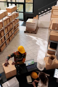 Diverse employees standing at counter desk in stockroom, preparing customer order for delivery. Storage room coworkers discussing merchandise quality control, working at inventory in warehouse