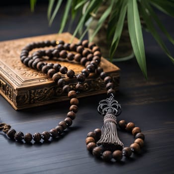 Bracelet with beads on a decorated book in the background of a green flower leaves. Ramadan as a time of fasting and prayer for Muslims. A time to meet with Allah.